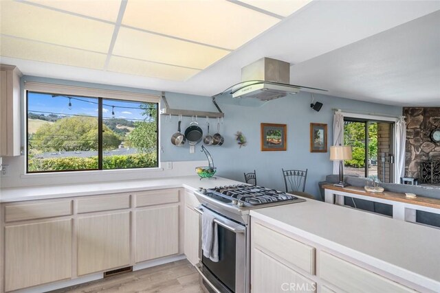 6058 Joan Pl, San Luis Obispo, CA 93401 - kitchen with stainless steel gas stove, light countertops, island range hood, and light wood-style flooring
