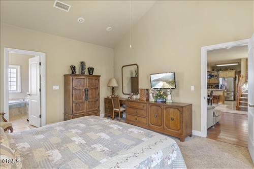 26941 Stirrup Way, Tehachapi, CA 93561 - bedroom featuring high vaulted ceiling, freestanding refrigerator, light colored carpet, baseboards, and ensuite bathroom