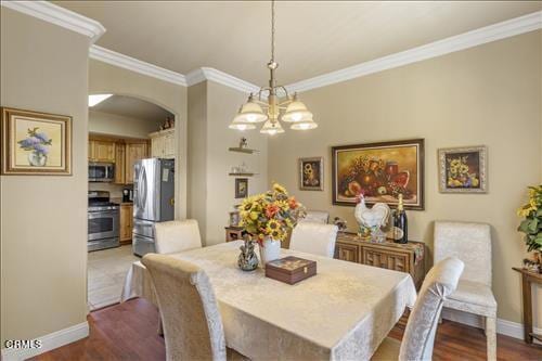 26941 Stirrup Way, Tehachapi, CA 93561 - dining room with arched walkways, crown molding, baseboards, a chandelier, and wood finished floors