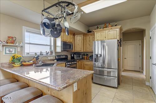 26941 Stirrup Way, Tehachapi, CA 93561 - kitchen with appliances with stainless steel finishes, a peninsula, arched walkways, a breakfast bar area, and light tile patterned flooring