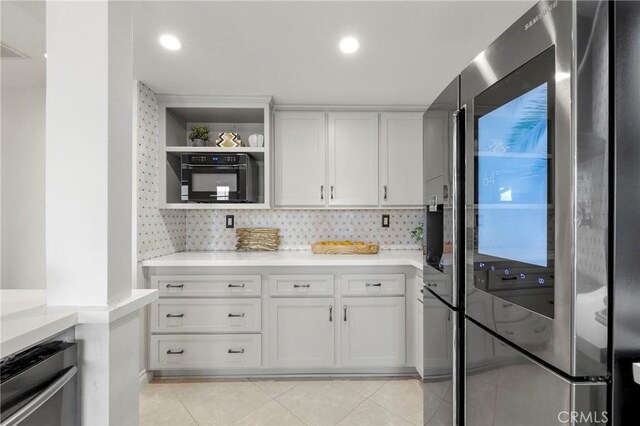 21011 Marin Unit 103, Lake Forest, CA 92630 - kitchen with stainless steel fridge, black oven, light tile patterned floors, white cabinets, and light countertops