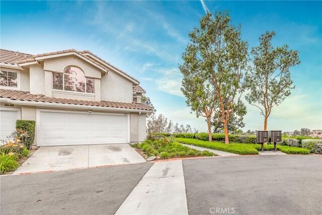 21011 Marin Unit 103, Lake Forest, CA 92630 - view of front facade featuring concrete driveway, stucco siding, an attached garage, and a tiled roof