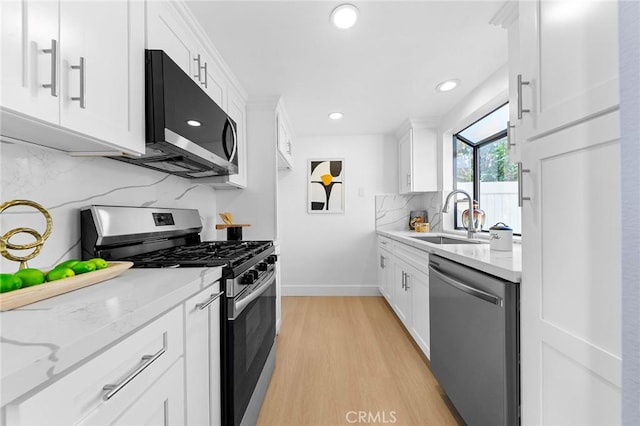 11636 Lambert Ave Unit 12, El Monte, CA 91732 - kitchen with appliances with stainless steel finishes, decorative backsplash, white cabinetry, light wood finished floors, and light stone counters