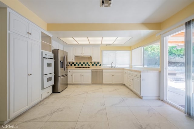 19941 Hiawatha St, Chatsworth, CA 91311 - kitchen featuring appliances with stainless steel finishes, open shelves, light countertops, white cabinetry, and light marble finish flooring