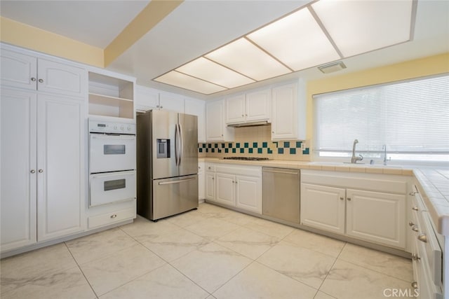 19941 Hiawatha St, Chatsworth, CA 91311 - kitchen with stainless steel appliances, white cabinetry, tile countertops, and open shelves