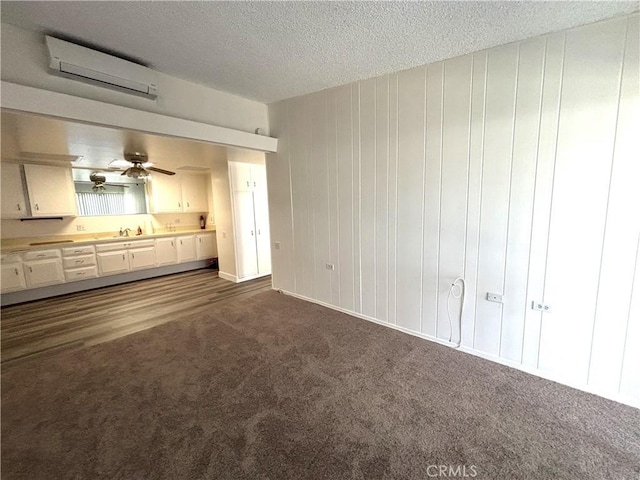 13540 Saint Andrews Dr Unit M14-4J, Seal Beach, CA 90740 - unfurnished living room with a wall unit AC, dark carpet, a textured ceiling, a sink, and ceiling fan