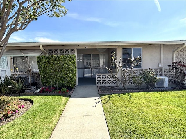 13540 Saint Andrews Dr Unit M14-4J, Seal Beach, CA 90740 - view of exterior entry with a lawn, stucco siding, and cooling unit
