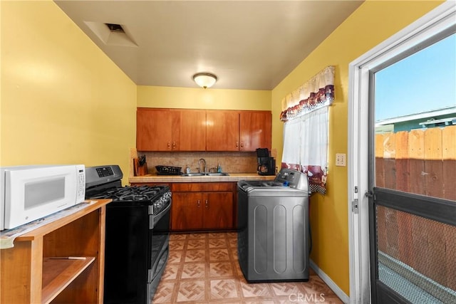 11909 Lowemont St, Norwalk, CA 90650 - kitchen featuring stainless steel gas range oven, washer / dryer, white microwave, and brown cabinets