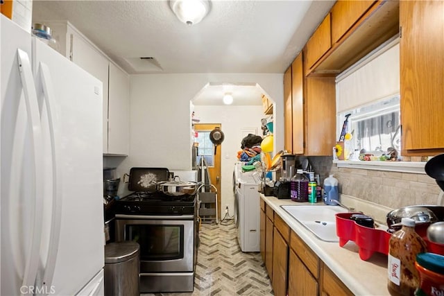 3339 E 4th St, Los Angeles, CA 90063 - kitchen with freestanding refrigerator, stainless steel gas range oven, light countertops, arched walkways, and brown cabinetry
