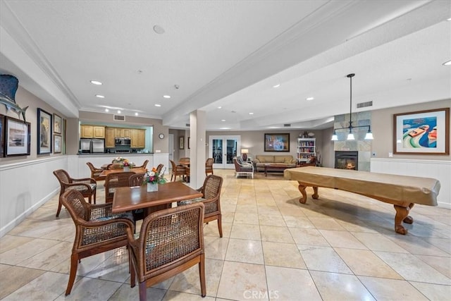 2750 Artesia Blvd Unit 337, Redondo Beach, CA 90278 - dining space featuring a tiled fireplace, a wainscoted wall, light tile patterned floors, ornamental molding, and a textured ceiling
