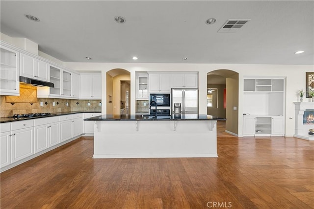 2123 Coconut Pl, Palmdale, CA 93551 - kitchen featuring stainless steel refrigerator with ice dispenser, arched walkways, under cabinet range hood, dark countertops, and recessed lighting