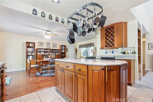 2482 Limestone Ct, Chino Hills, CA 91709 - kitchen featuring light countertops, brown cabinets, light tile patterned floors, a center island, and a ceiling fan