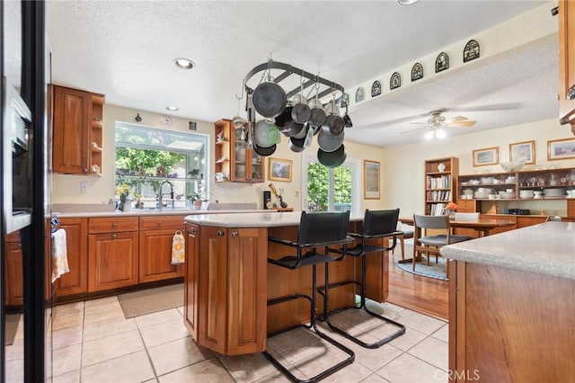 2482 Limestone Ct, Chino Hills, CA 91709 - kitchen featuring open shelves, light countertops, plenty of natural light, brown cabinetry, and a textured ceiling