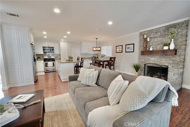 7642 Rhone Ln, Huntington Beach, CA 92647 - living area with light wood-type flooring, crown molding, a stone fireplace, recessed lighting, and baseboards