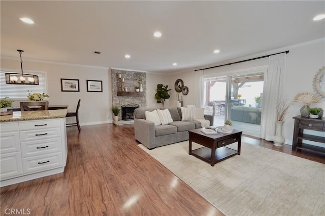 7642 Rhone Ln, Huntington Beach, CA 92647 - living room featuring crown molding, dark wood-style flooring, baseboards, recessed lighting, and a stone fireplace