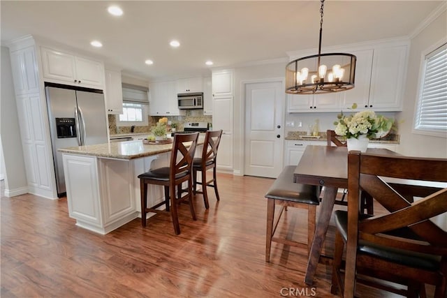 7642 Rhone Ln, Huntington Beach, CA 92647 - kitchen featuring stainless steel appliances, a chandelier, wood finished floors, white cabinetry, and a kitchen island