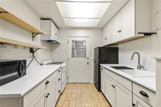 1634 Bayview Dr, Hermosa Beach, CA 90254 - kitchen with white gas range oven, black microwave, a sink, light wood-style floors, and freestanding refrigerator