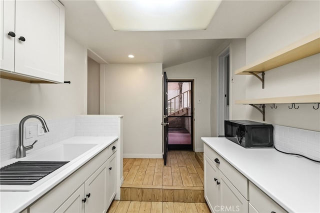 1634 Bayview Dr, Hermosa Beach, CA 90254 - kitchen featuring black microwave, open shelves, a sink, white cabinets, and light wood finished floors