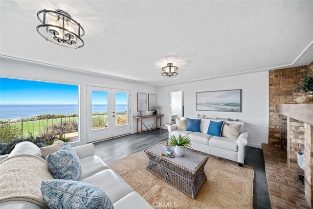 1000 Park Ave, Cayucos, CA 93430 - living area with wood finished floors, a chandelier, a water view, and a brick fireplace