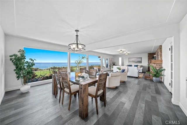 1000 Park Ave, Cayucos, CA 93430 - dining area featuring a chandelier, dark wood-style flooring, baseboards, and a water view