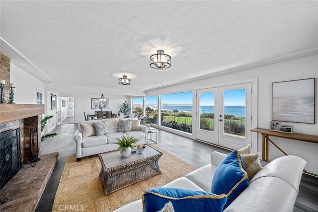1000 Park Ave, Cayucos, CA 93430 - living room with french doors, a brick fireplace, a water view, and a textured ceiling