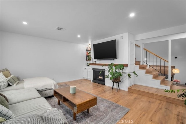 5465 Newcastle Ave Unit 6, Encino, CA 91316 - living room featuring light wood-style flooring, stairway, a warm lit fireplace, and recessed lighting