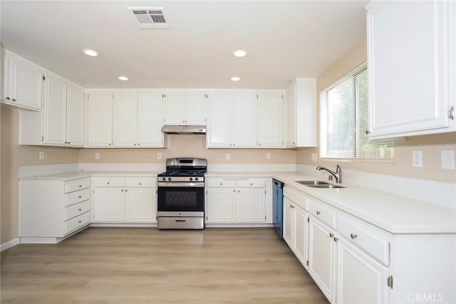 44124 Sundance Ct, Lancaster, CA 93535 - kitchen with stainless steel gas range, under cabinet range hood, white cabinetry, recessed lighting, and a sink