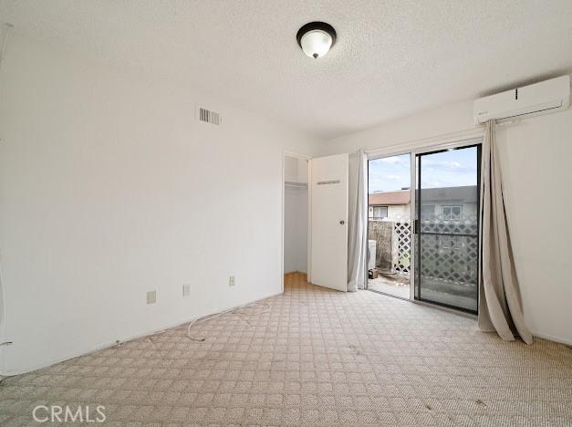 4177 Walnut Grove Ave, Rosemead, CA 91770 - unfurnished bedroom with a wall unit AC, light carpet, access to exterior, and a textured ceiling