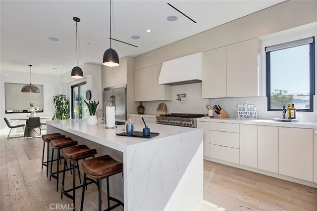 622 1st Pl, Hermosa Beach, CA 90254 - kitchen featuring custom exhaust hood, high end fridge, modern cabinets, light wood-type flooring, and white cabinets