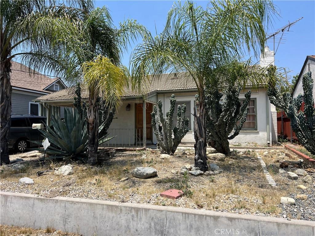 316 W Lugonia Ave, Redlands, CA 92374 - view of property hidden behind natural elements with stucco siding, a tile roof, and a chimney