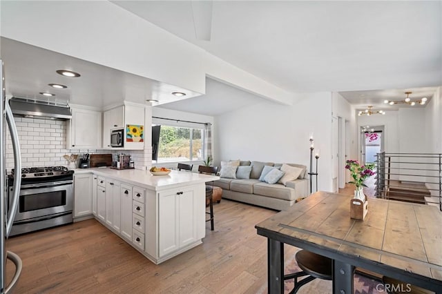 1637 Spreckels Ln, Redondo Beach, CA 90278 - kitchen with stainless steel appliances, a peninsula, wall chimney exhaust hood, backsplash, and white cabinetry