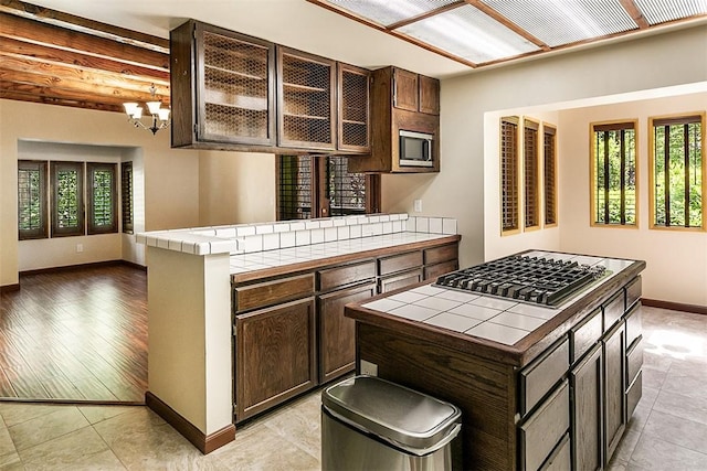 760 Kuffel Canyon Rd, Lake Arrowhead, CA 92385 - kitchen with tile counters, stainless steel appliances, dark brown cabinets, and a chandelier
