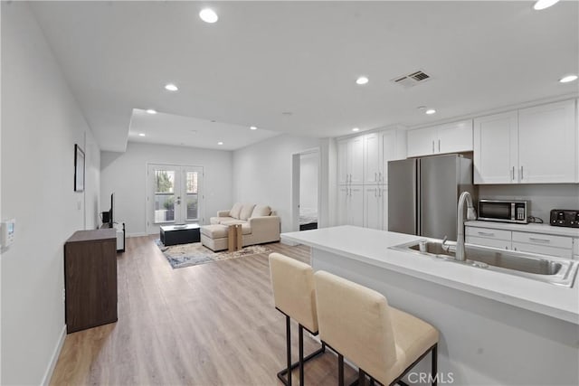 419 N Chandler Ave Unit 305, Monterey Park, CA 91754 - kitchen with stainless steel appliances, white cabinets, a kitchen breakfast bar, light countertops, and light wood-type flooring