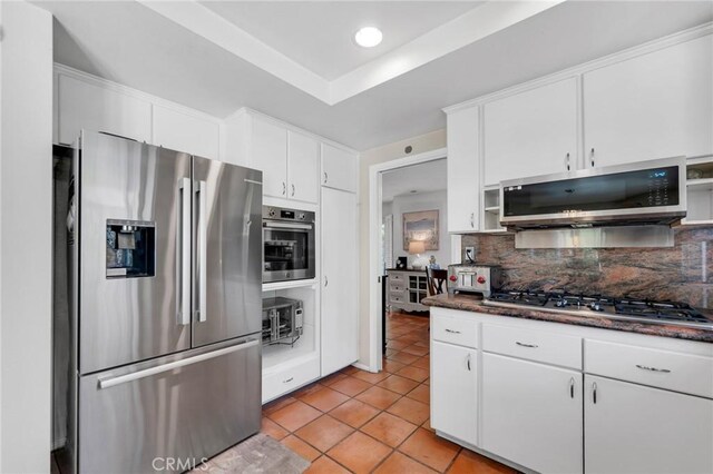 12045 Falcon Crest Way, Porter Ranch, CA 91326 - kitchen with appliances with stainless steel finishes, backsplash, light tile patterned floors, dark countertops, and white cabinets