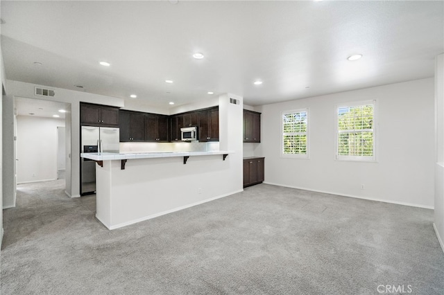61 Silverado, Irvine, CA 92618 - kitchen with stainless steel appliances, light colored carpet, a kitchen bar, dark brown cabinetry, and recessed lighting