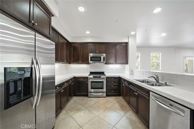 61 Silverado, Irvine, CA 92618 - kitchen with appliances with stainless steel finishes, dark brown cabinetry, light tile patterned floors, recessed lighting, and tile counters