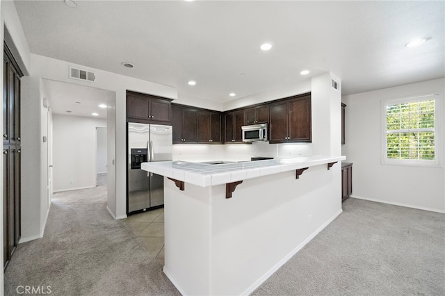 61 Silverado, Irvine, CA 92618 - kitchen with appliances with stainless steel finishes, light colored carpet, tile countertops, dark brown cabinetry, and recessed lighting