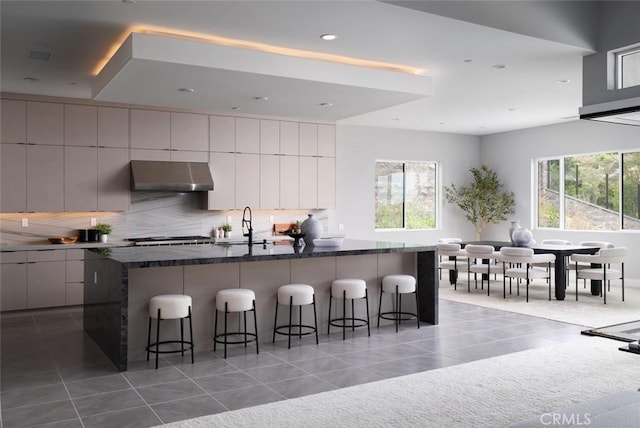 18510 Boulder Blf, Silverado, CA 92676 - kitchen featuring under cabinet range hood, light tile patterned floors, modern cabinets, a kitchen breakfast bar, and recessed lighting