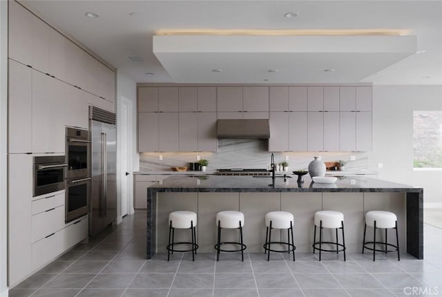18510 Boulder Blf, Silverado, CA 92676 - kitchen with gray cabinetry, appliances with stainless steel finishes, tasteful backsplash, a breakfast bar, and extractor fan
