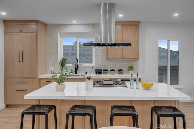 3649 Mount Vernon Dr, View Park, CA 90008 - kitchen featuring island exhaust hood, light brown cabinets, light wood-type flooring, a kitchen bar, and recessed lighting