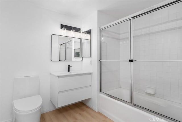 4426 Ventura Canyon Ave Unit 204, Sherman Oaks, CA 91423 - bathroom featuring vanity, combined bath / shower with glass door, toilet, wood finished floors, and baseboards