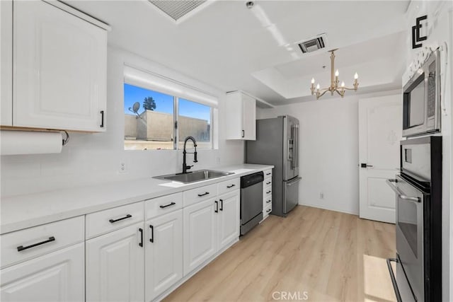 4426 Ventura Canyon Ave Unit 204, Sherman Oaks, CA 91423 - kitchen featuring appliances with stainless steel finishes, a sink, light wood finished floors, white cabinetry, and a chandelier