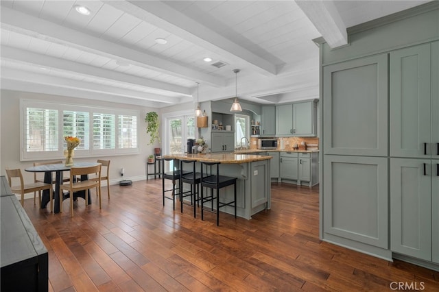 732 Hilary Ln, Redlands, CA 92373 - kitchen featuring stainless steel microwave, a breakfast bar area, light stone counters, dark wood-type flooring, and beam ceiling
