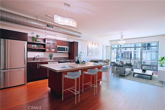 1111 S Grand Ave Unit 702, Los Angeles, CA 90015 - kitchen with stainless steel appliances, a kitchen island, wood finished floors, and a breakfast bar area