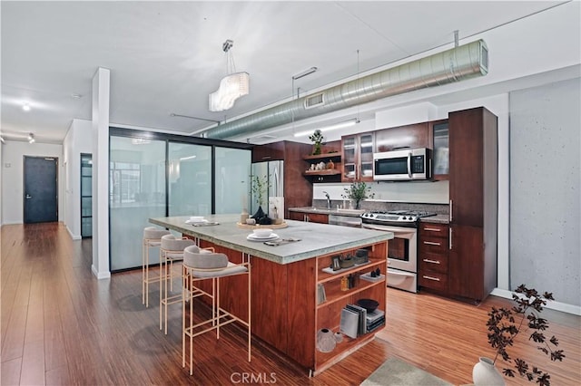 1111 S Grand Ave Unit 702, Los Angeles, CA 90015 - kitchen with open shelves, stainless steel appliances, a kitchen bar, a kitchen island, and light wood-style floors