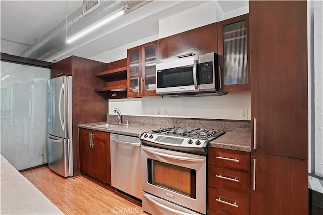 1111 S Grand Ave Unit 702, Los Angeles, CA 90015 - kitchen featuring stainless steel appliances, a sink, light wood finished floors, open shelves, and glass insert cabinets