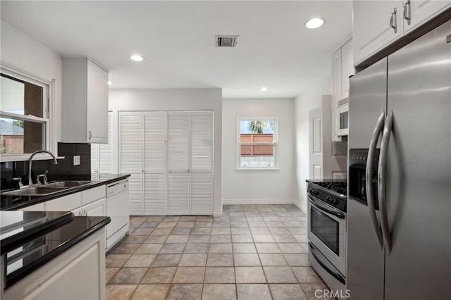 6515 Amigo Ave, Reseda, CA 91335 - kitchen featuring stainless steel appliances, dark countertops, a sink, white cabinetry, and tasteful backsplash
