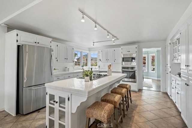 233 Elaine Way, Pismo Beach, CA 93449 - kitchen with appliances with stainless steel finishes, tile counters, white cabinetry, and a kitchen island