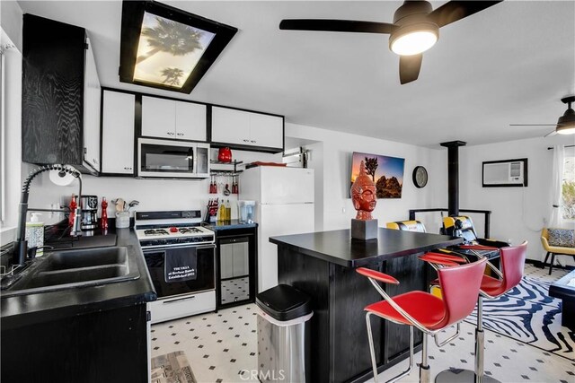 49490 Big Morongo Canyon Rd, Morongo Valley, CA 92256 - kitchen with white appliances, ceiling fan, a sink, dark countertops, and white cabinetry