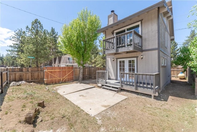 2100 1st Ln, Big Bear City, CA 92314 - rear view of property featuring a balcony, french doors, a fenced backyard, and a chimney